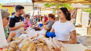 Personas en la Feria del Pan de Grijota con productos de panadería