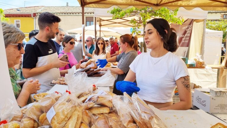 Personas en la Feria del Pan de Grijota con productos de panadería