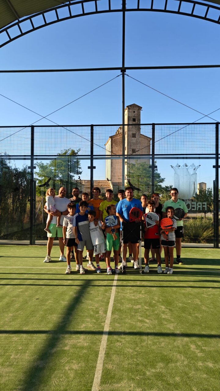 Grupo de niños y adultos en una pista de pádel