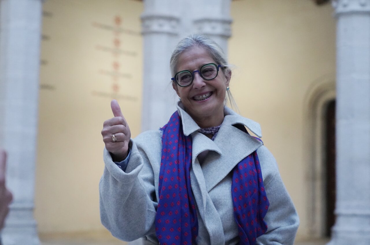 Mujer sonriente con pulgar hacia arriba en un entorno universitario