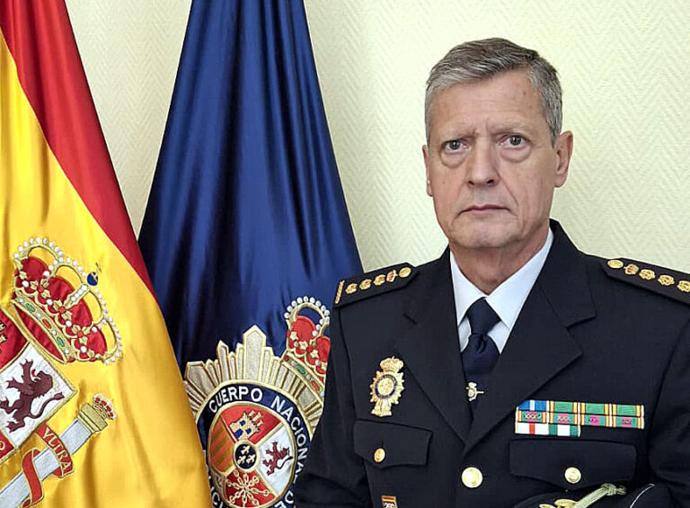 Jesús del Amo en uniforme de policía junto a banderas de España