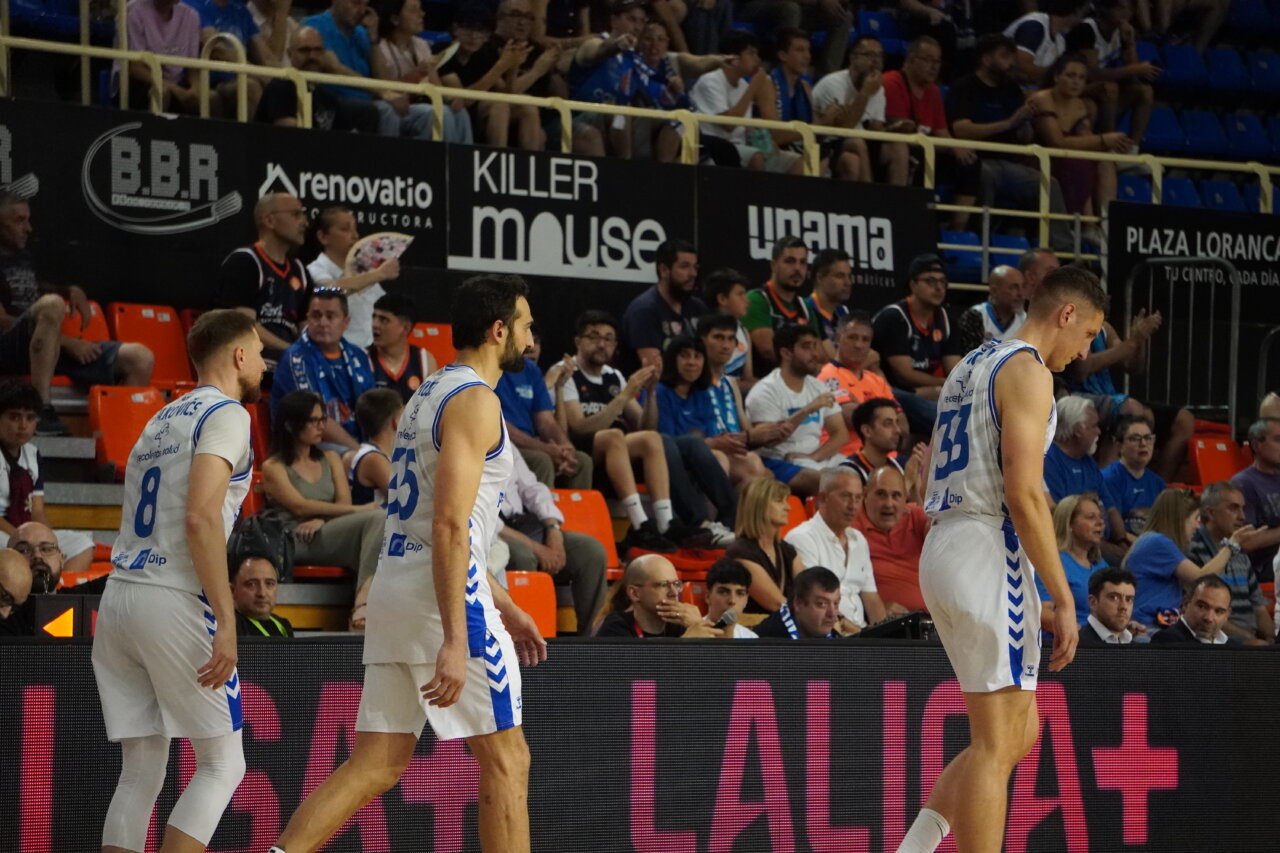 Jugadores de baloncesto en un partido con público animado.