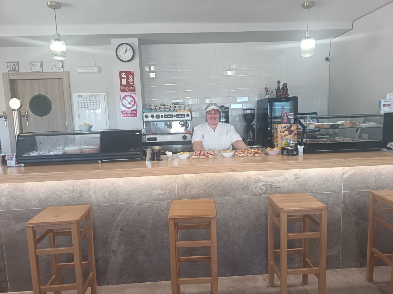 Interior del Bar-Restaurante La Parada con una mujer sonriente detrás de la barra.