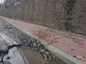 Estado deteriorado de la travesía en Barruelo de Santullán con baches y agua acumulada