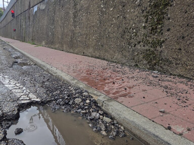 Estado deteriorado de la travesía en Barruelo de Santullán con baches y agua acumulada