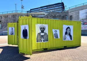 Contenedor amarillo con retratos en el Museo Migrante en Palencia
