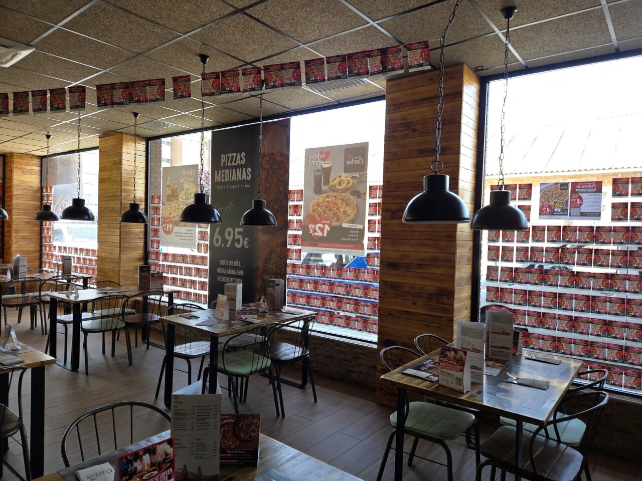 Interior de la Pizzería Carlos con mesas y decoración de pizza