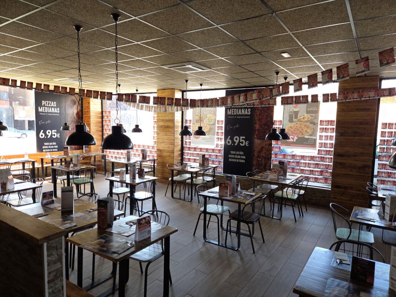 Interior de la Pizzería Carlos con mesas y decoración festiva