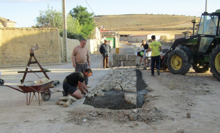 Grupo de personas trabajando en la mejora de un camino en el pueblo.