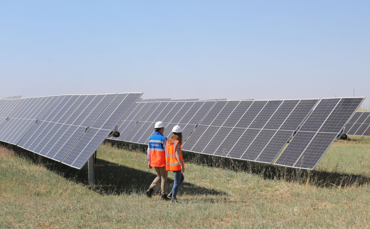 Dos personas caminando entre paneles solares en una planta fotovoltaica