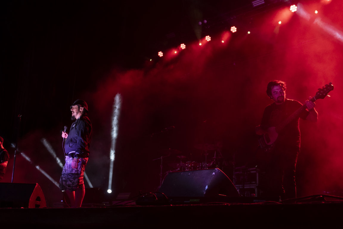 Actuación en el festival Astudillo Punk Rock con luces rojas y músicos en el escenario.