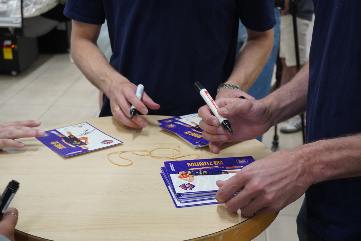 Manos firmando tarjetas en un evento de despedida