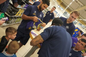 Jugadores de baloncesto firmando camisetas a niños en un evento