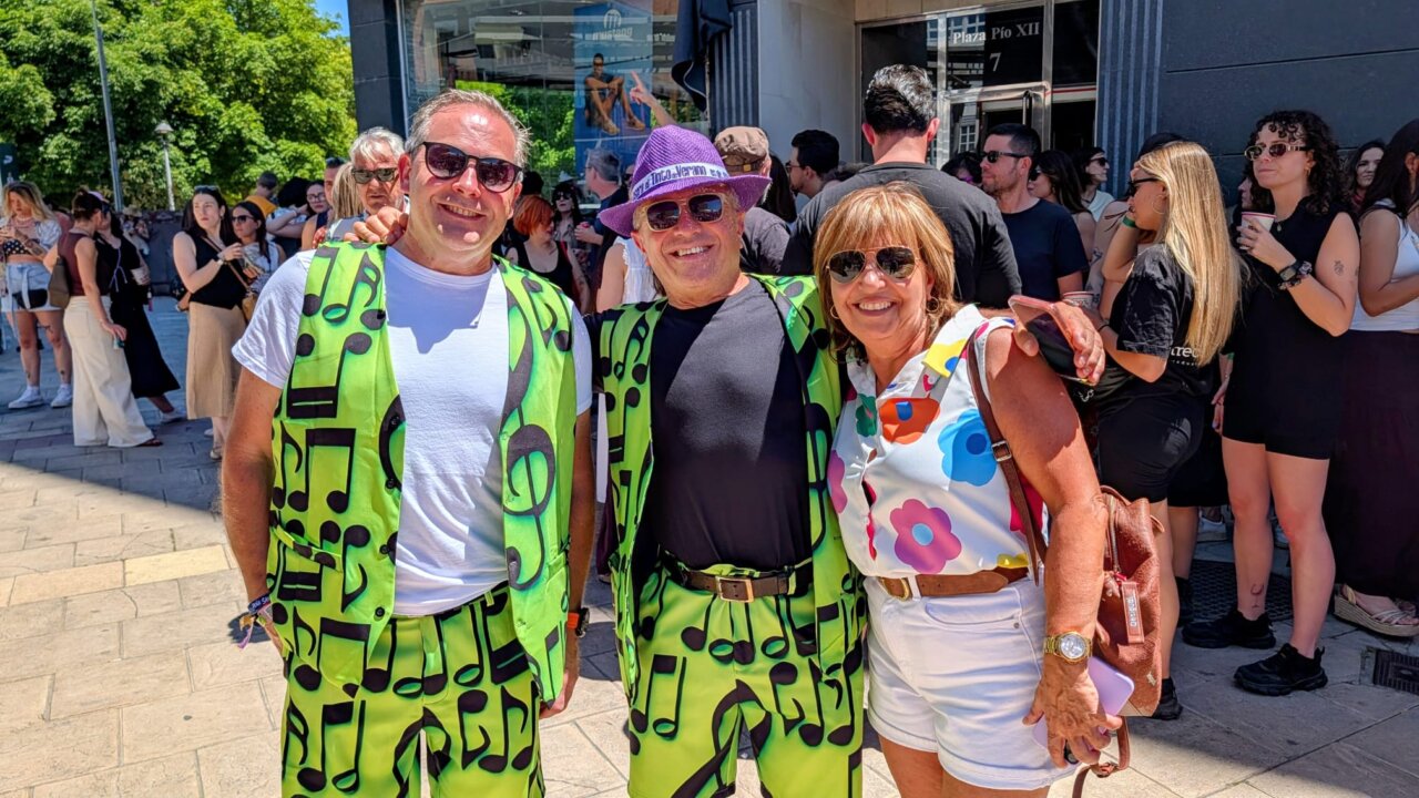 Tres personas con trajes coloridos en un evento musical al aire libre