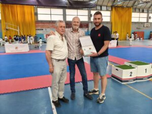 Tres hombres sosteniendo un premio en el campeonato de karate en Venta de Baños.