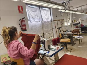 Mujer trabajando en un taller textil con prendas de moda sostenible