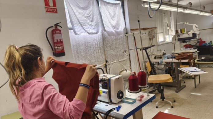 Mujer trabajando en un taller textil con prendas de moda sostenible