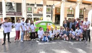 Grupo de estudiantes de arte junto a un coche clásico decorado en Palencia