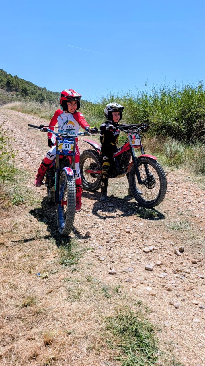 Dos jóvenes pilotos en motocicletas de trial en un camino rural