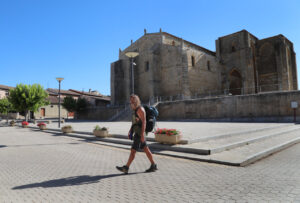 Peregrino caminando frente a un monumento del Camino de Santiago