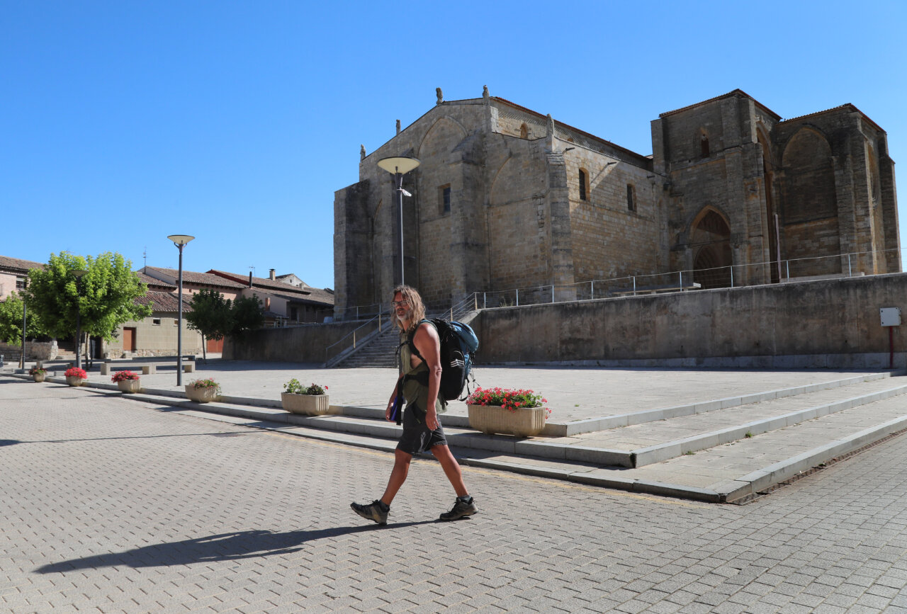 Peregrino caminando frente a un monumento del Camino de Santiago
