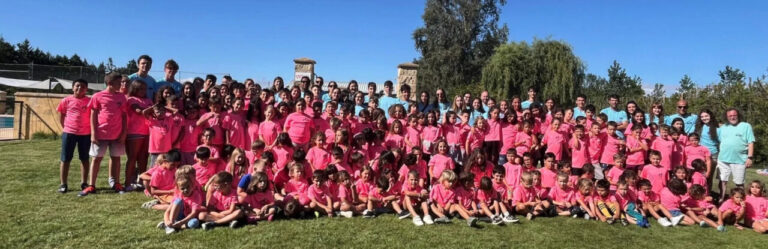 Grupo de niños y adultos en campamento urbano con camisetas rosas