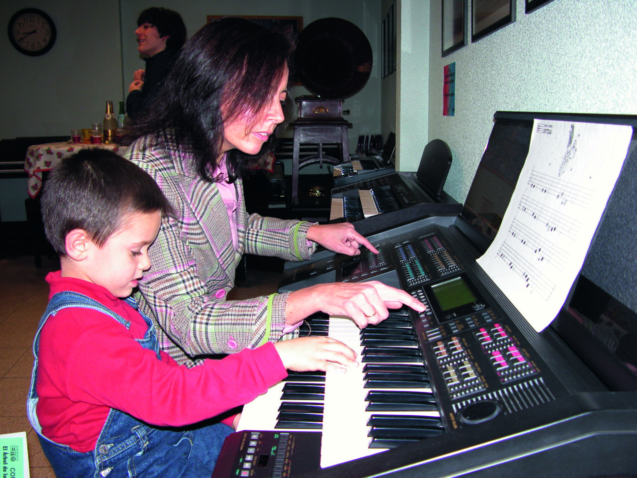Una mujer y un niño tocando un teclado musical juntos.
