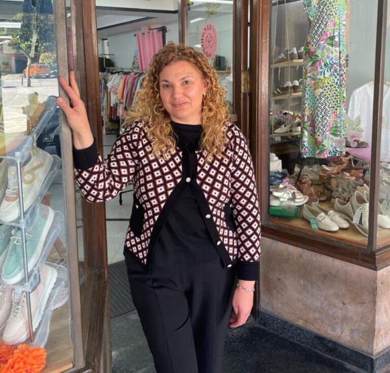 Mujer de pie en la entrada de una tienda de moda en Aguilar de Campoo