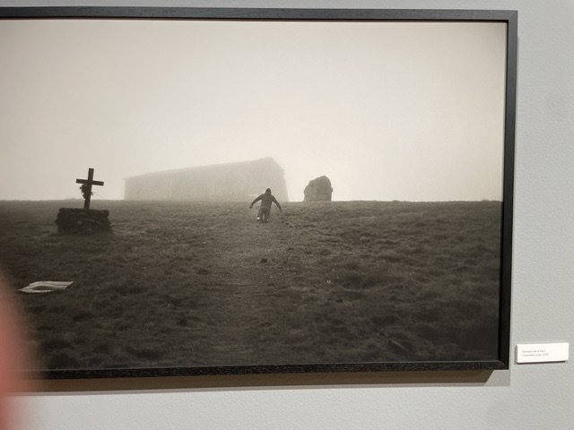Fotografía en blanco y negro de una persona caminando hacia una edificación en la niebla.