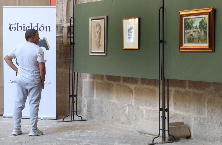 Hombre observando pinturas en una exposición de arte