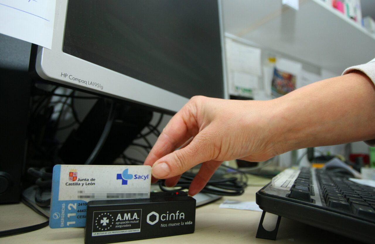 Persona utilizando tarjeta sanitaria en un ordenador para receta electrónica