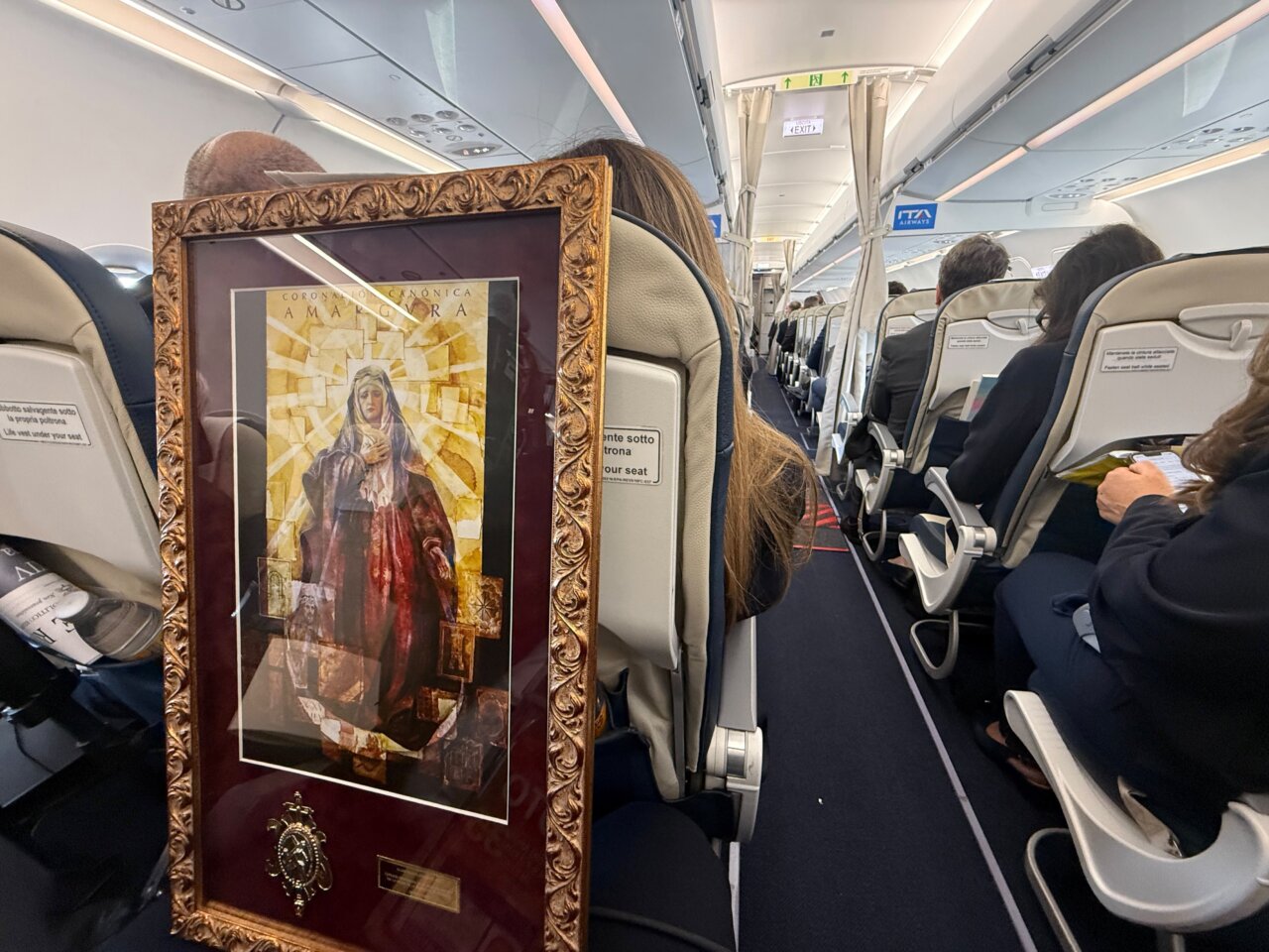 Enmarcación de la Virgen de la Amargura en un avión con pasajeros