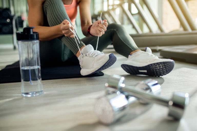 Mujer atando sus zapatillas deportivas en un gimnasio
