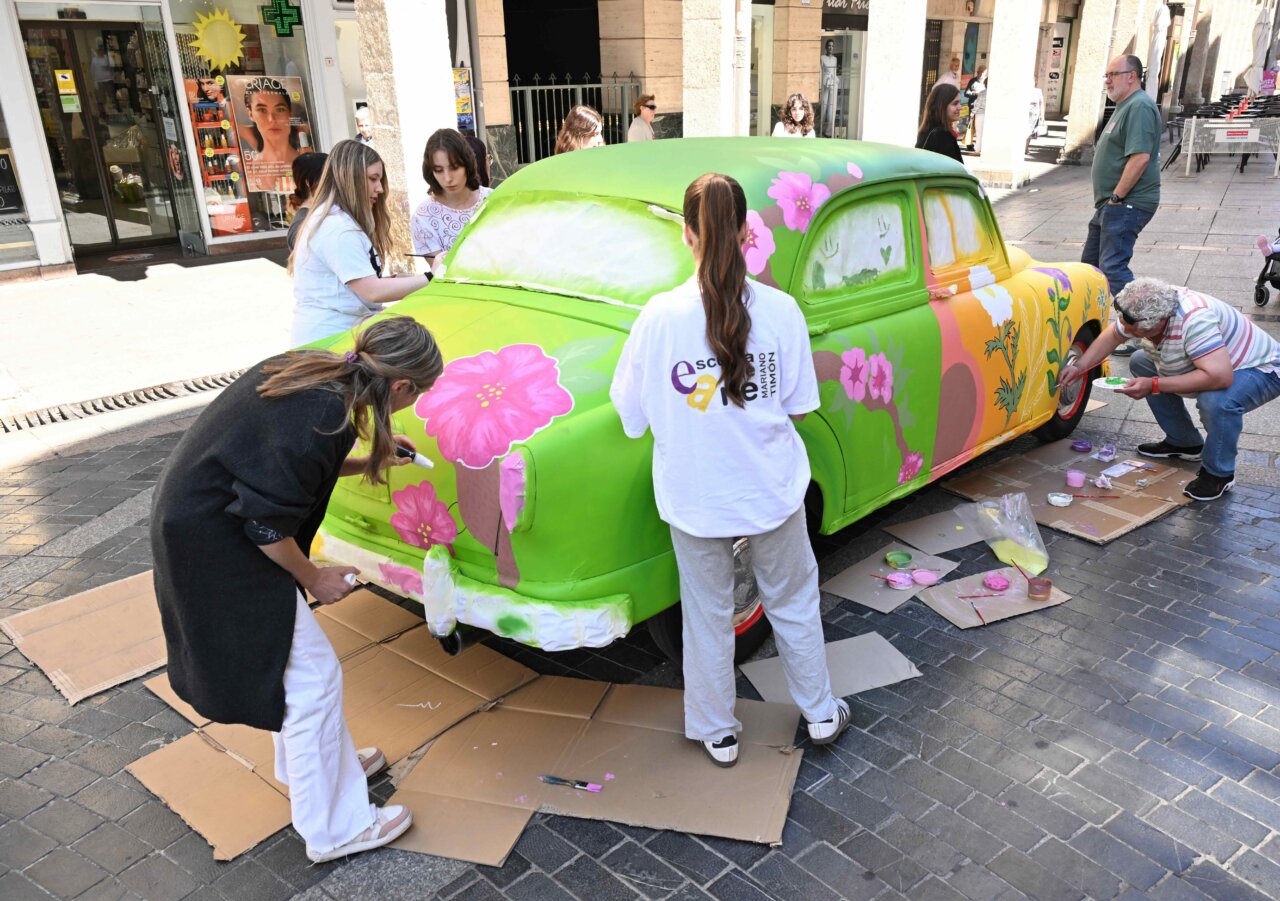 Alumnos pintando un coche clásico en la Calle Mayor de Palencia