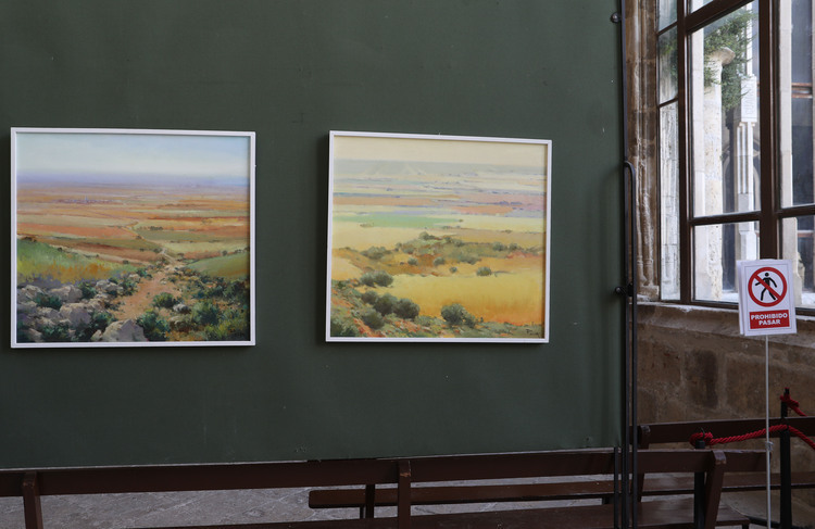 Dos pinturas de paisajes enmarcadas en una pared verde