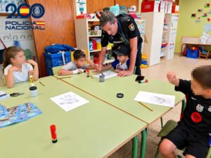 Un agente de policía interactuando con niños en un aula durante un curso educativo.