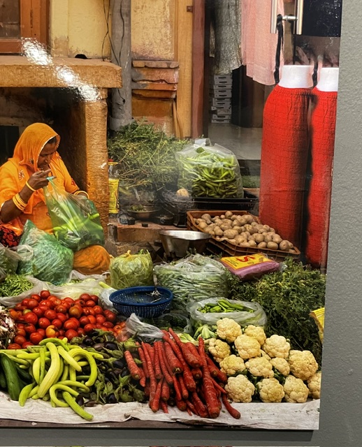Mujer en un mercado de Bharat rodeada de verduras frescas