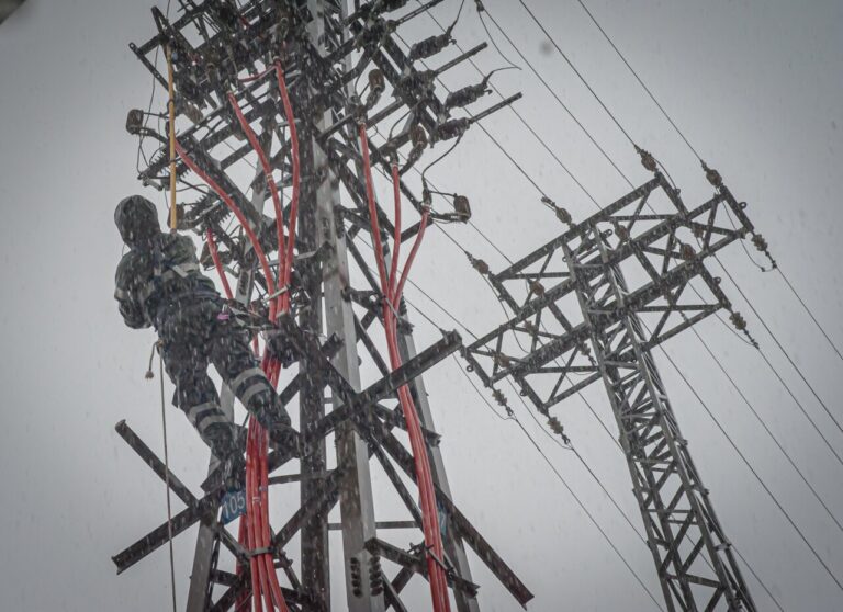 Técnico trabajando en una torre eléctrica durante una tormenta