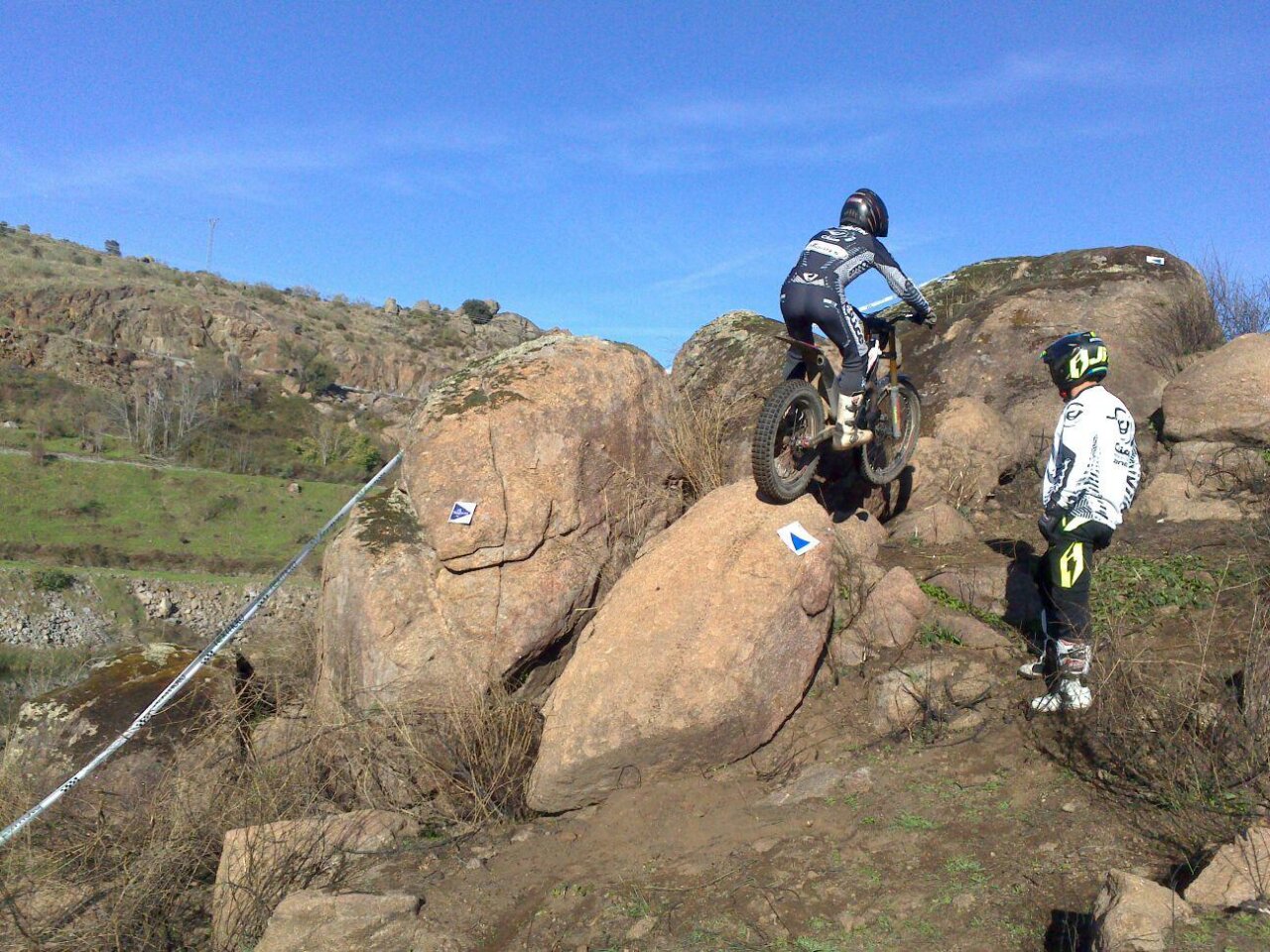 Piloto de trial superando obstáculos en una competición al aire libre
