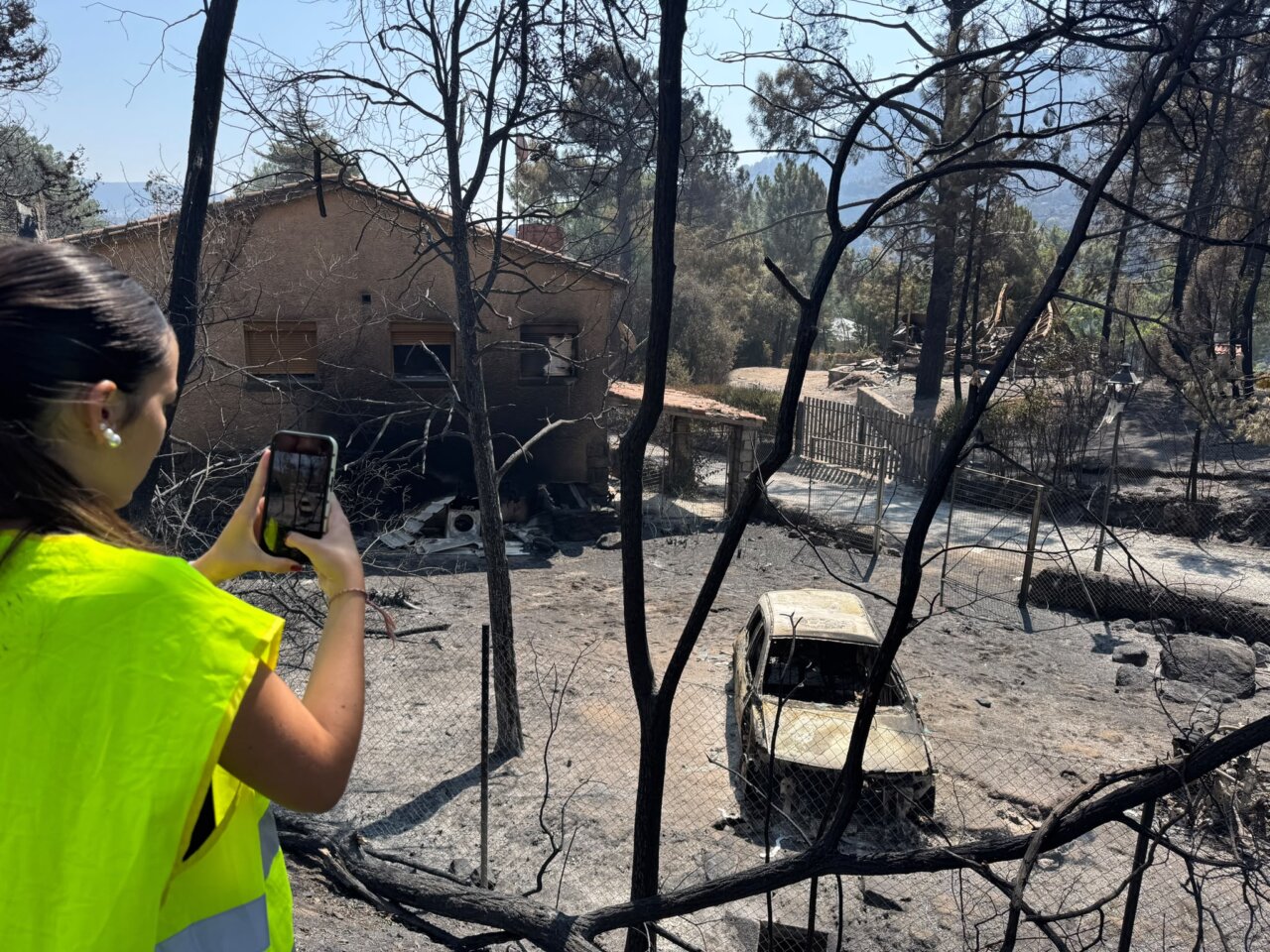 Mujer fotografiando un camping destruido por un incendio forestal en Ávila