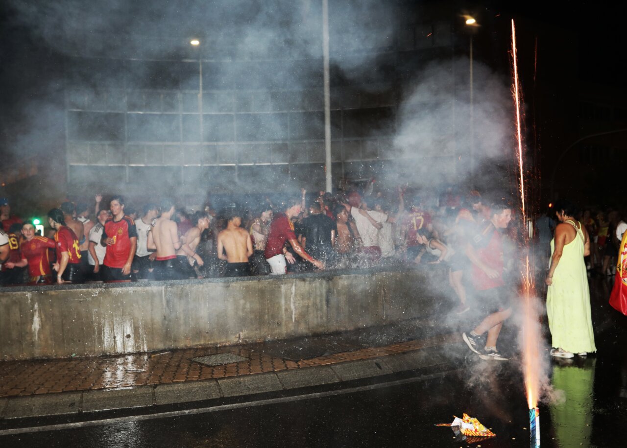 Aficionados celebrando la victoria de España en la calle con fuegos artificiales