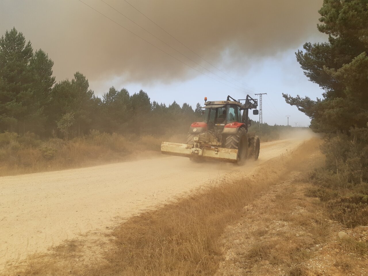 Tractor trabajando en un camino forestal durante un incendio