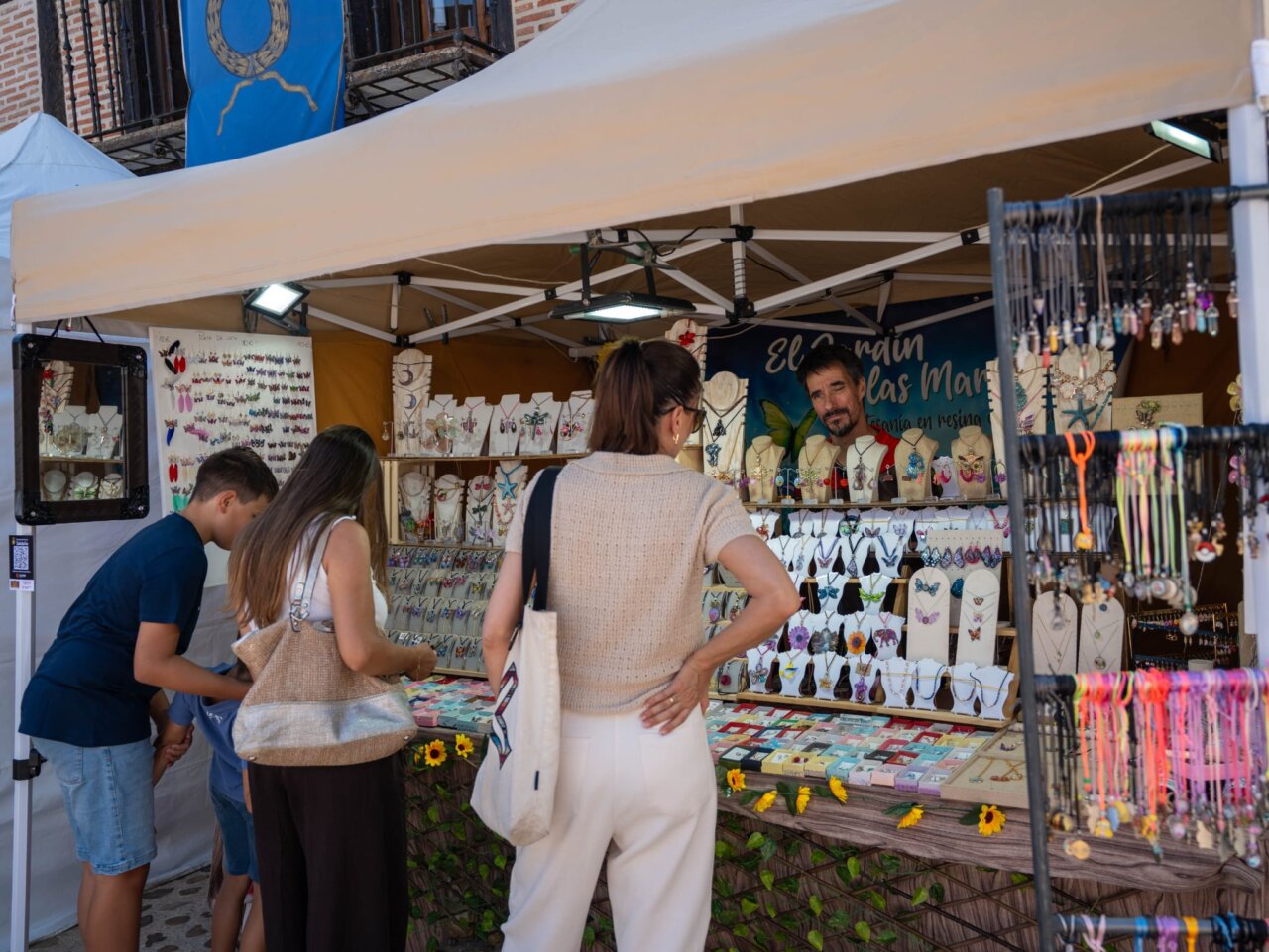 Visitantes explorando un puesto de joyería en el Mercado Romano de Saldaña