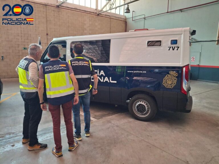 Agentes de la Policía Nacional observando una furgoneta policial en un garaje.