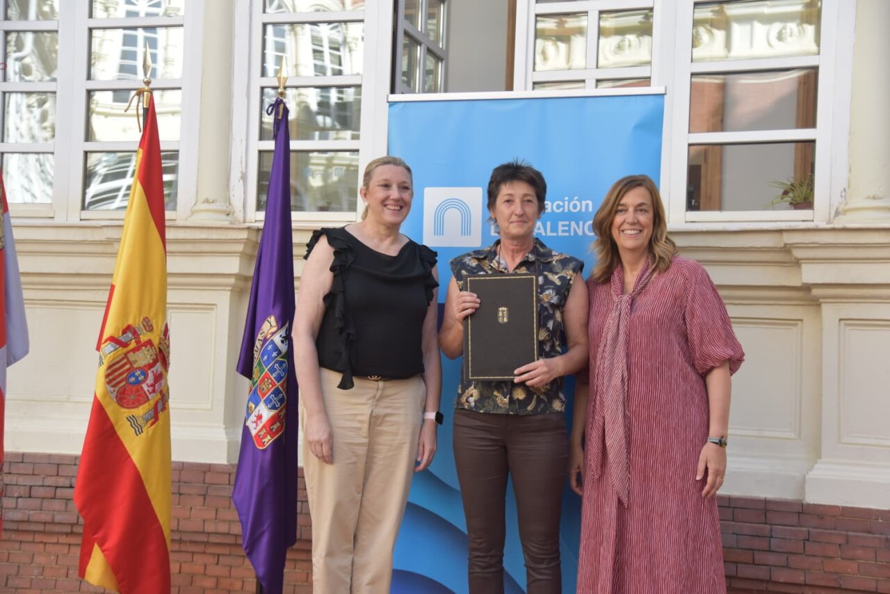 Tres mujeres sosteniendo un documento en un evento sobre vivienda social