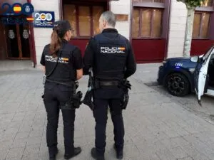 Dos agentes de la Policía Nacional en Palencia observando un vehículo policial.