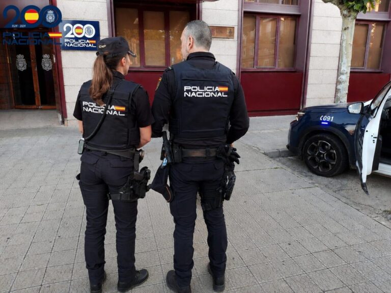 Dos agentes de la Policía Nacional en Palencia observando un vehículo policial.