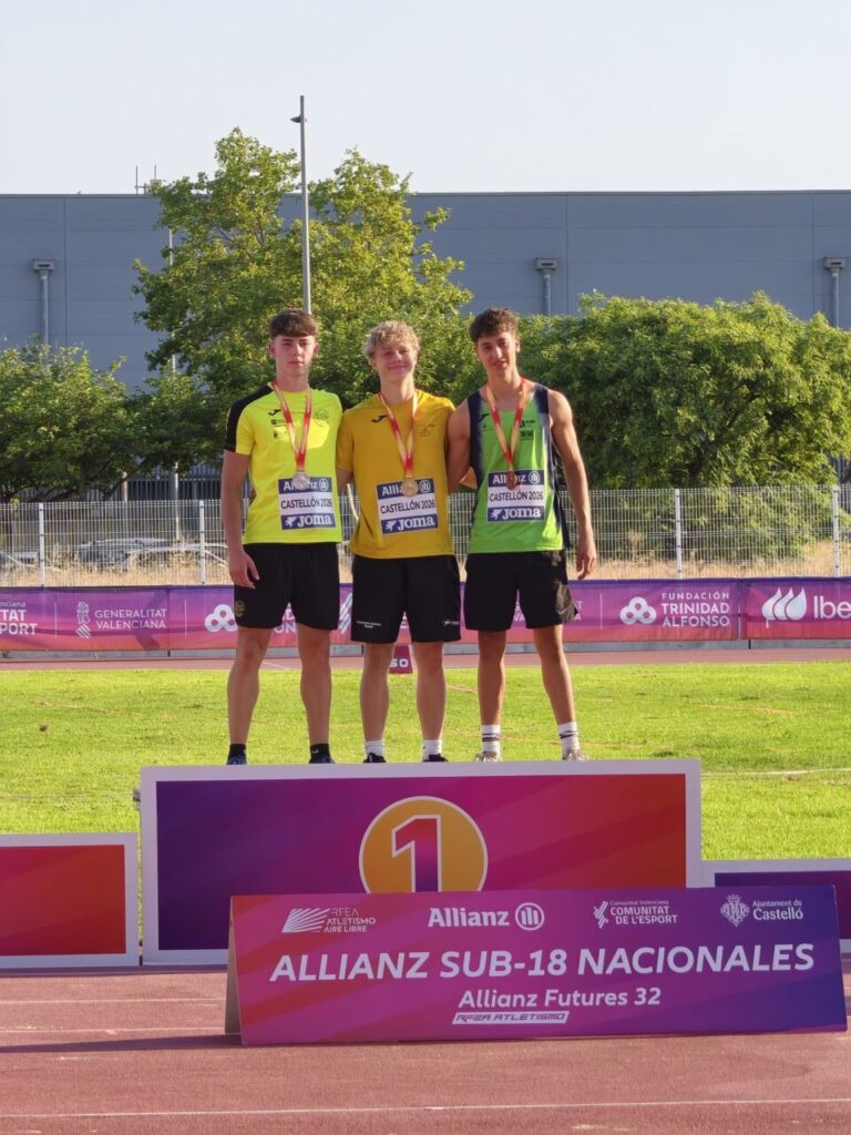 Tres atletas en el podio con medallas en un evento deportivo.
