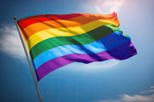 Bandera del orgullo LGTBI ondeando bajo un cielo azul claro