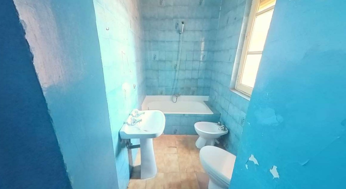 Baño en estado deficiente con azulejos azules y bañera
